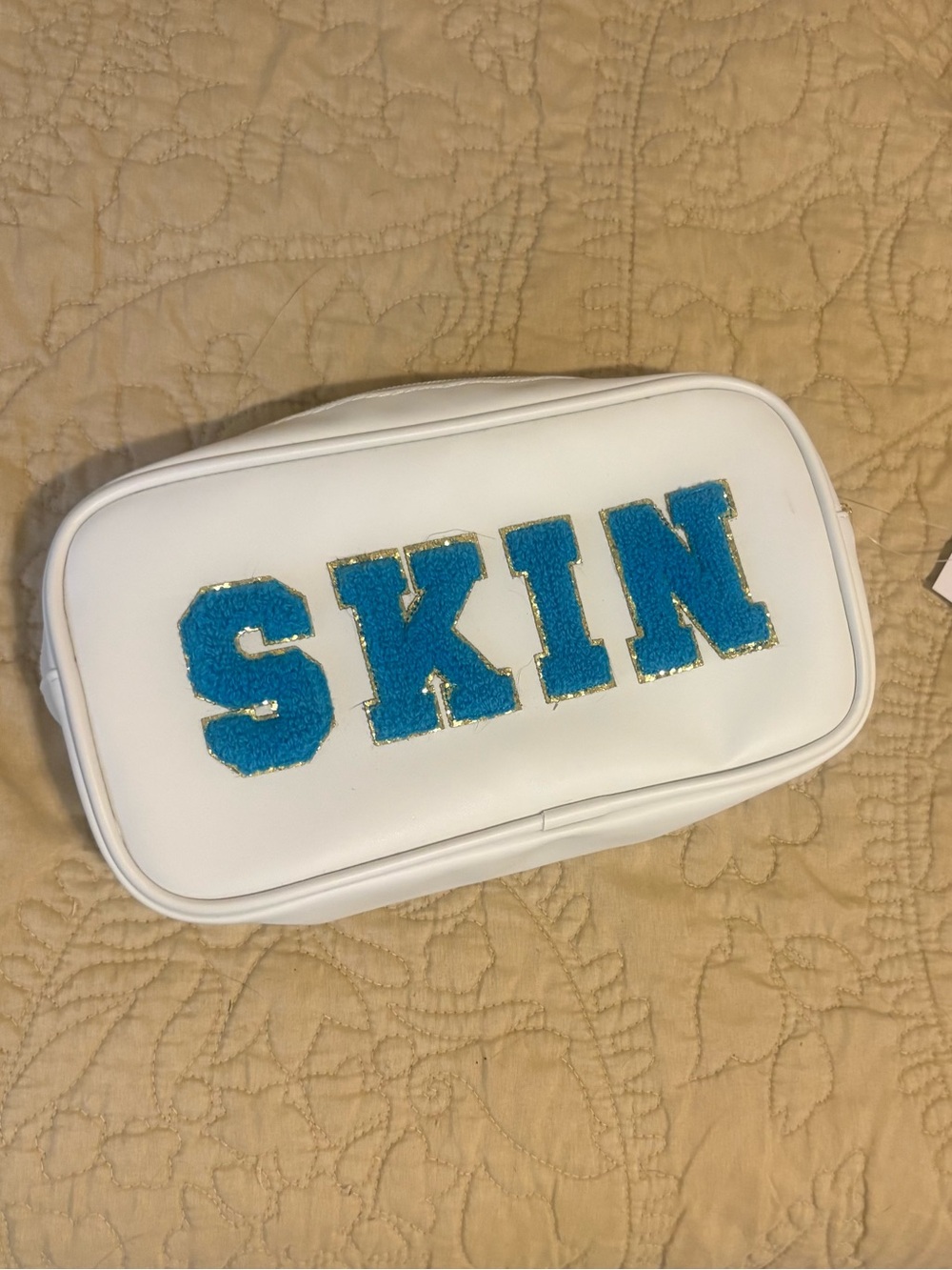 Neutrogena White Kids Pouch with Blue 'SKIN' Letters and Gold Trim